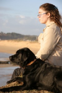 photo d'une jeune femme assise avec son chien devant la mer